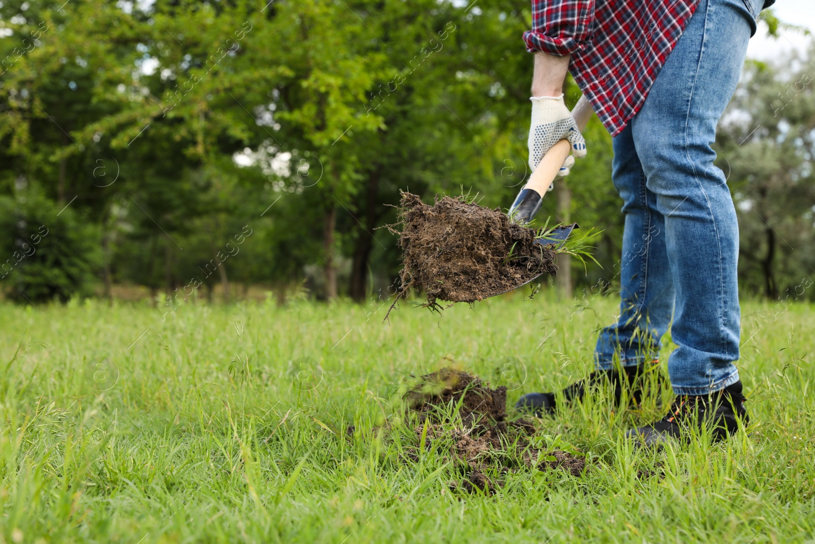 Photo of Worker digging soil with shovel outdoors, closeup