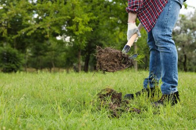 Worker digging soil with shovel outdoors, closeup