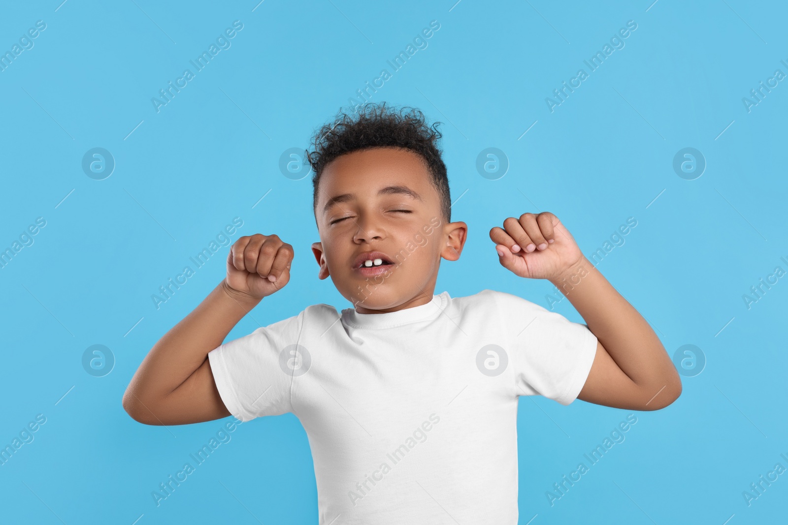 Photo of Boy stretching on light blue background. Insomnia problem