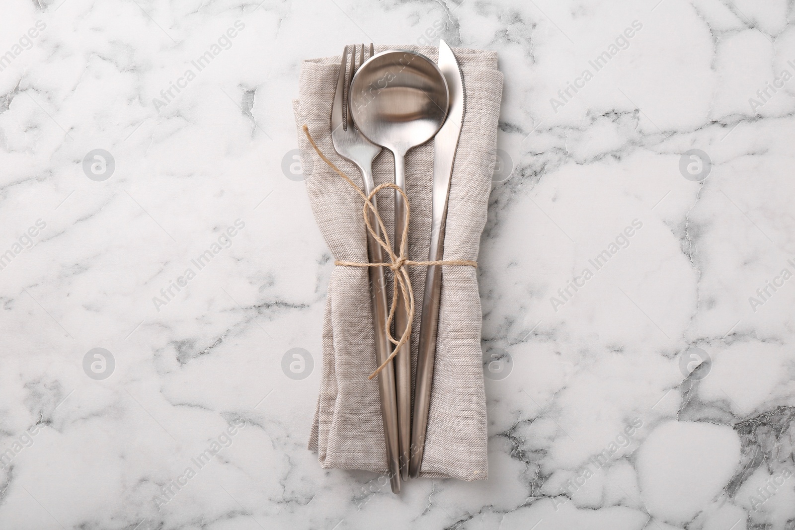 Photo of Set of stylish cutlery and napkin on white marble table, top view