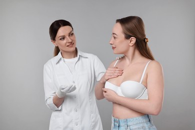 Photo of Mammologist checking woman's breast on gray background