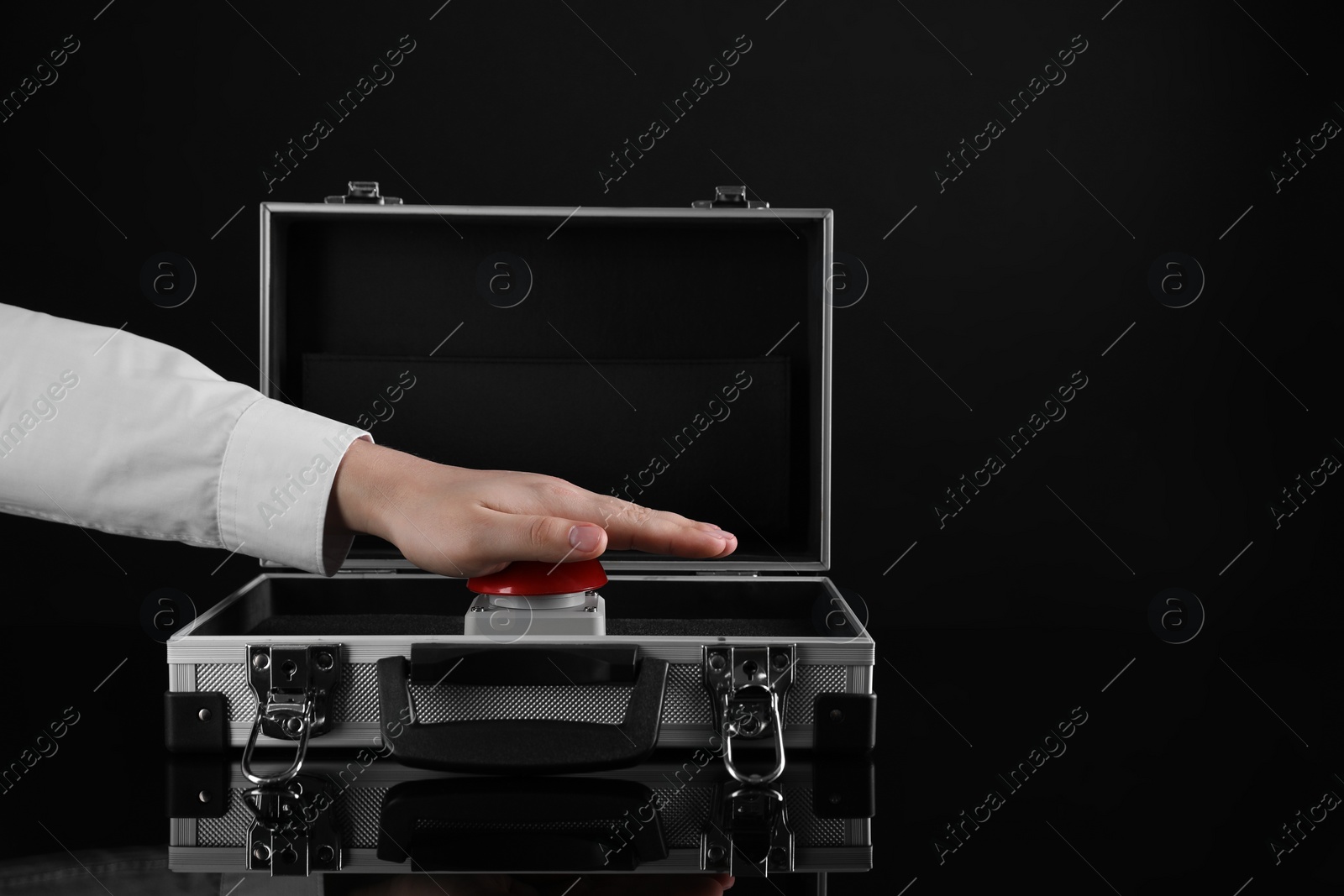 Photo of Man pressing red button of nuclear weapon on black background, closeup with space for text. War concept