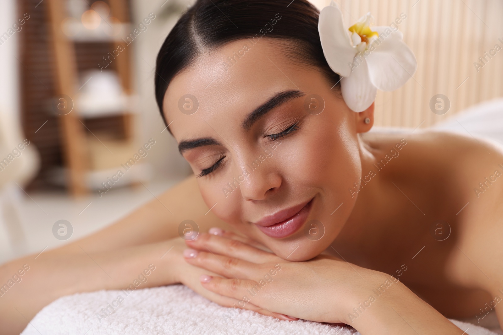 Photo of Young woman resting on massage couch in spa salon, closeup