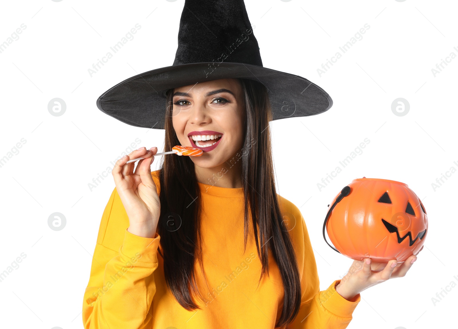 Photo of Beautiful woman wearing witch costume with Jack O'Lantern candy container for Halloween party on white background