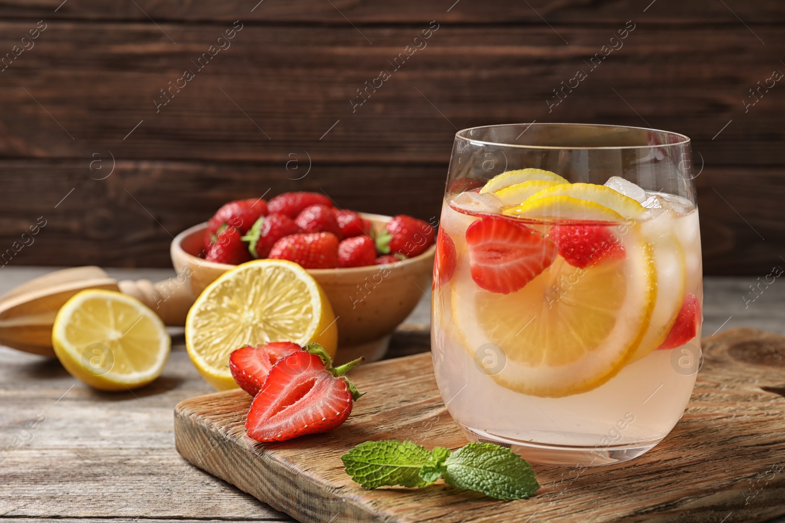 Photo of Natural lemonade with strawberries in glass on table