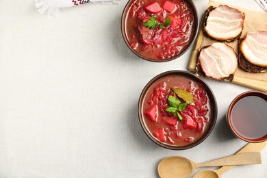 Photo of Stylish brown clay bowl with Ukrainian borsch served on white tablecloth, flat lay. Space for text