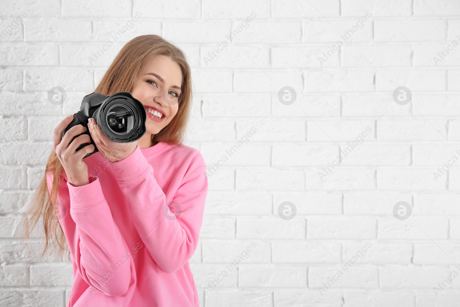 Photo of Female photographer with camera on brick background