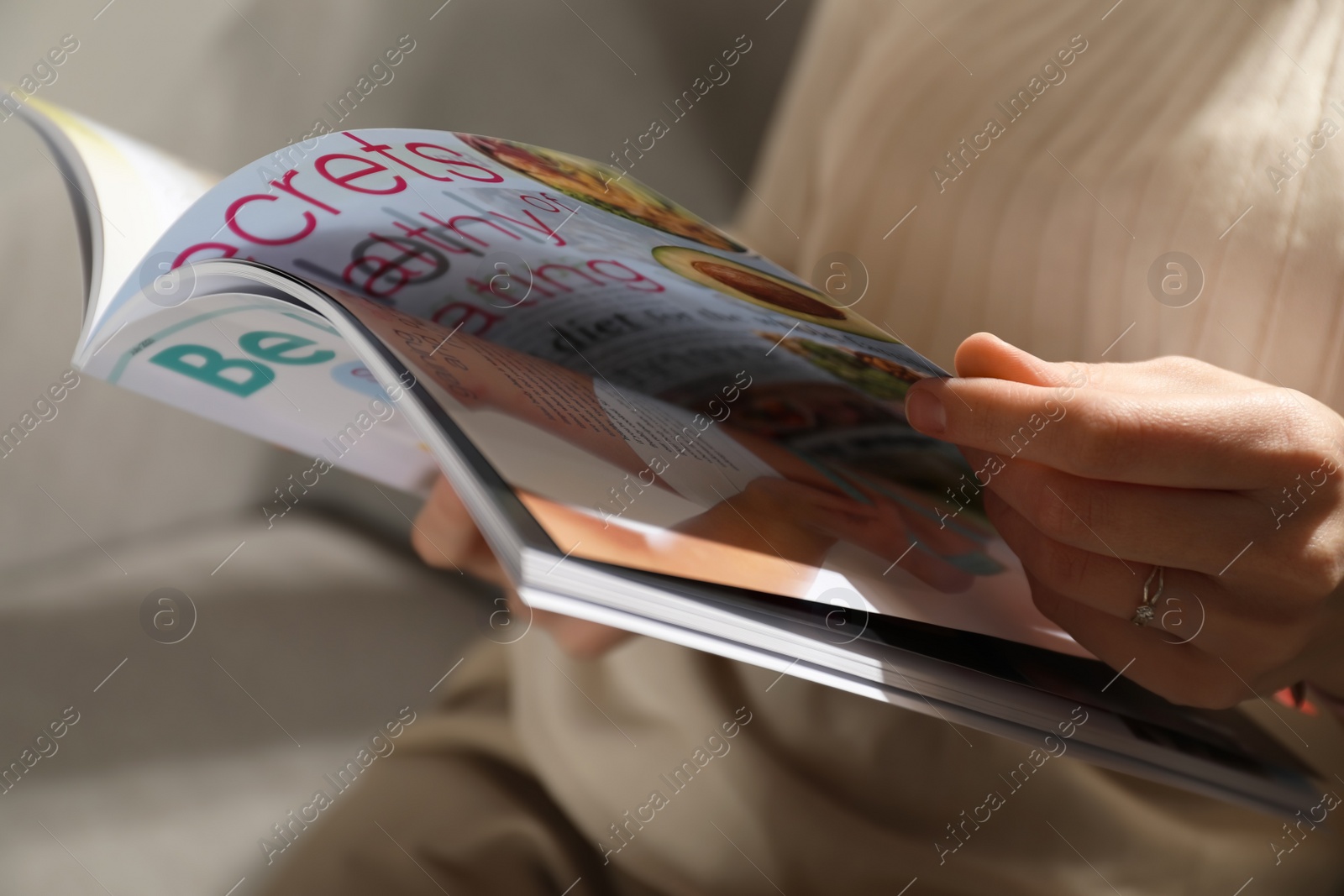 Photo of Woman reading healthy food magazine on sofa at home, closeup