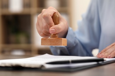 Photo of Woman stamping document at table, closeup view