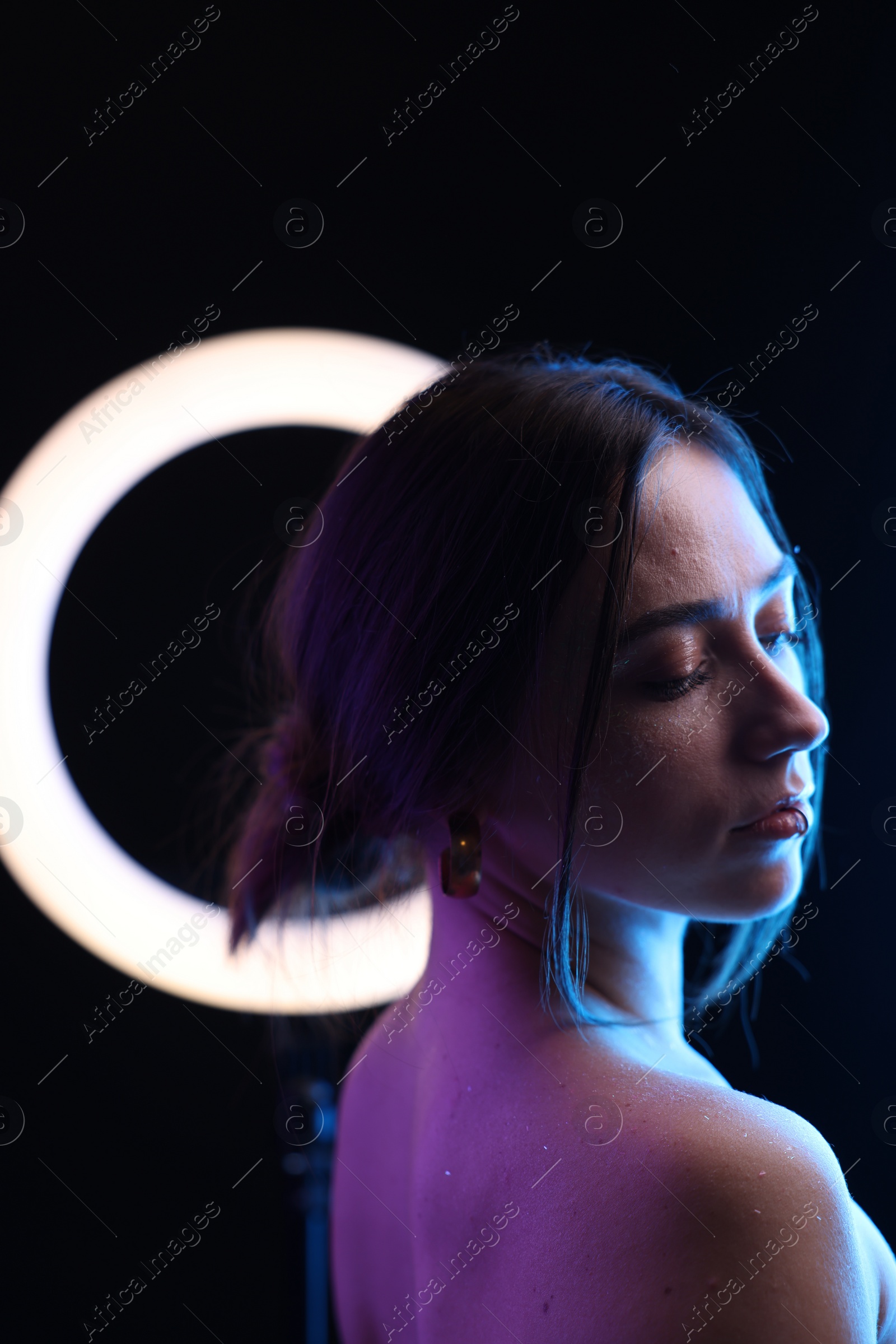 Photo of Beautiful woman and ring lamp on dark background in neon lights