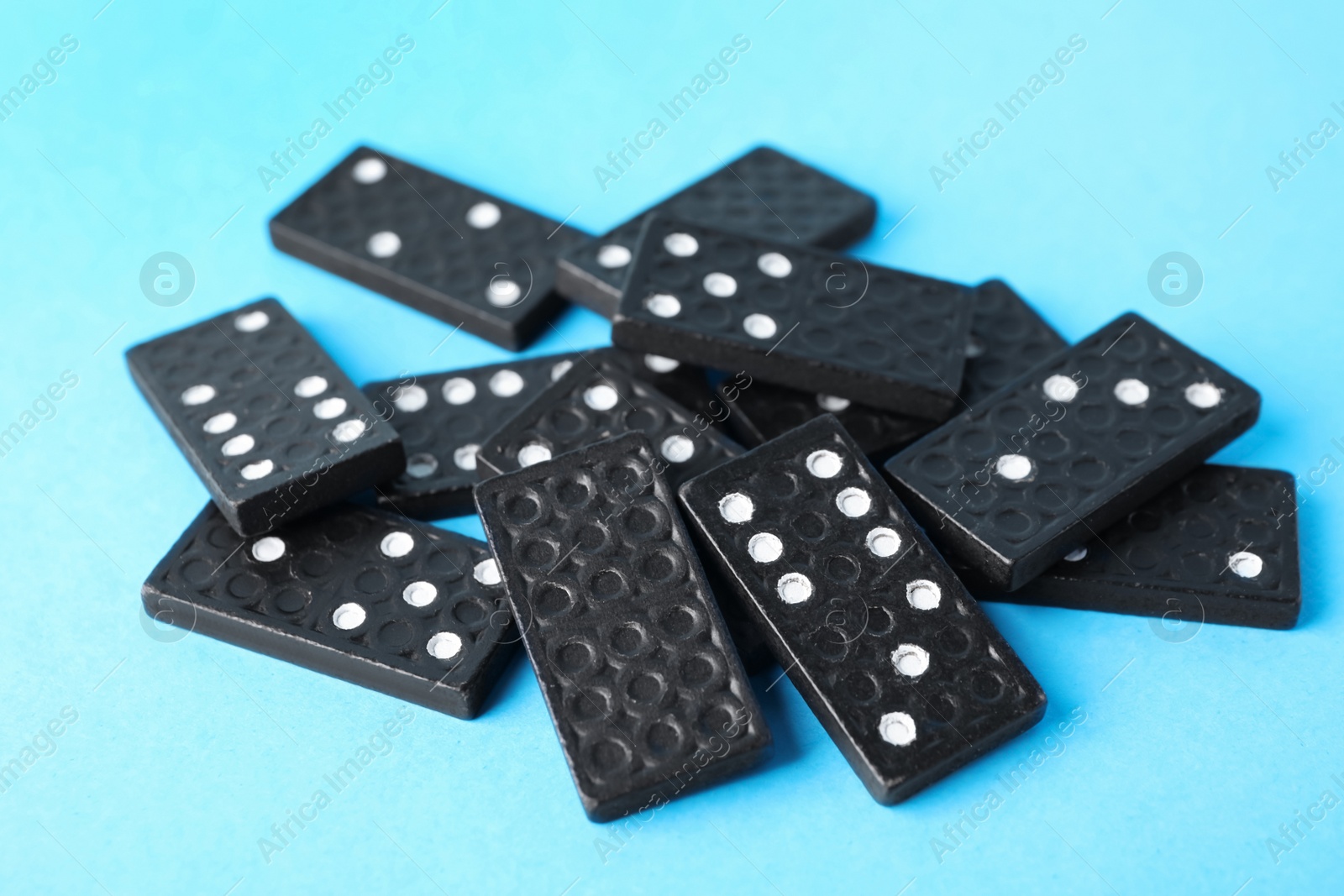 Photo of Pile of black domino tiles on turquoise background