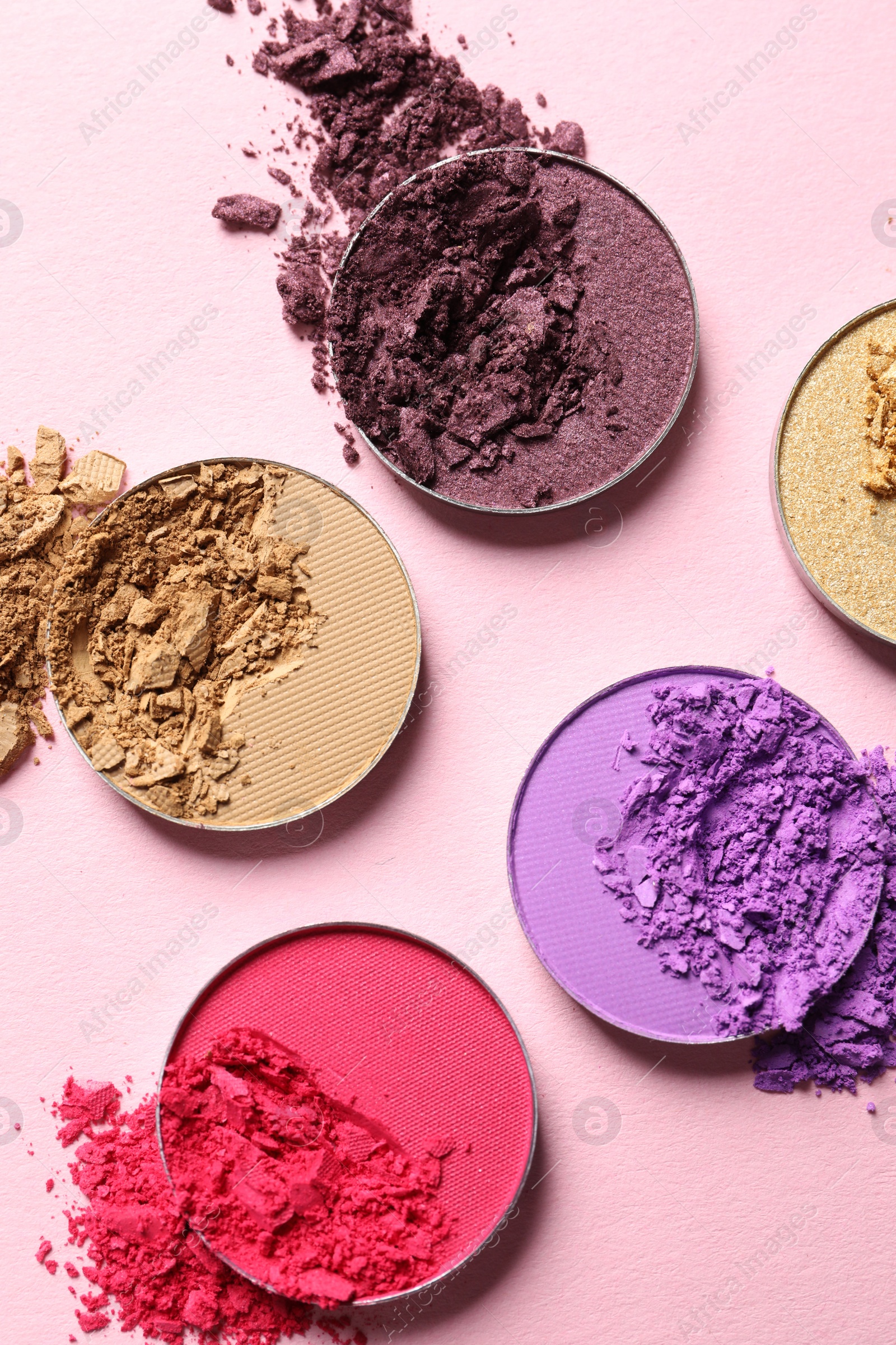 Photo of Different crushed eye shadows on pink background, flat lay