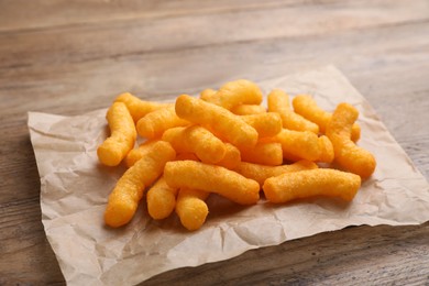 Photo of Many tasty cheesy corn puffs on wooden table