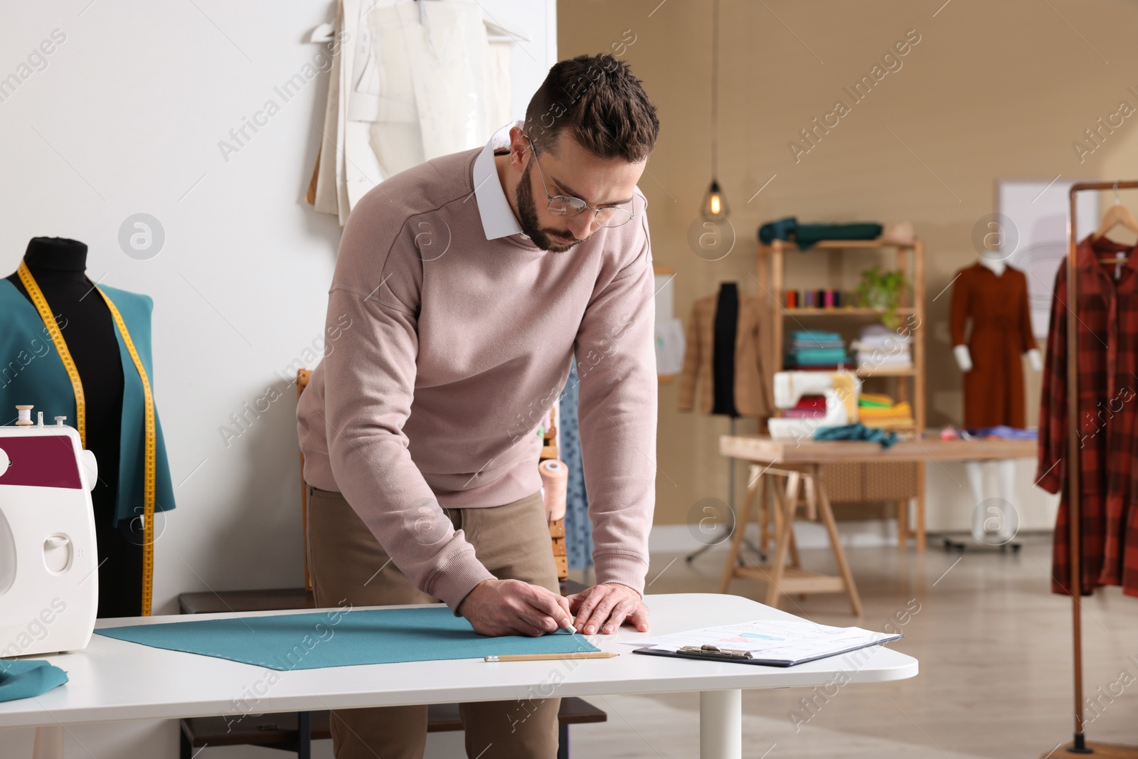 Photo of Dressmaker marking fabric with chalk in workshop