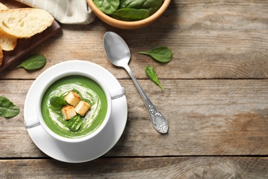 Photo of Flat lay composition with fresh vegetable detox soup made of spinach with croutons in dish and space for text on wooden table