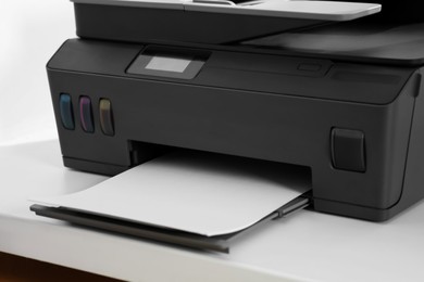 Photo of Modern printer with paper on white table, closeup