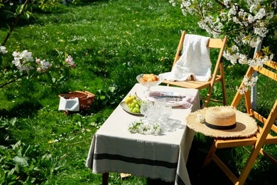 Photo of Stylish table setting with beautiful spring flowers in garden on sunny day