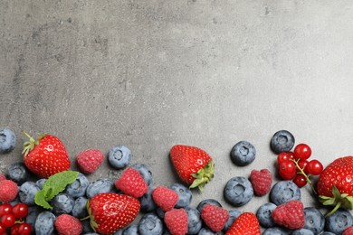 Photo of Different fresh berries on grey background, flat lay. Space for text