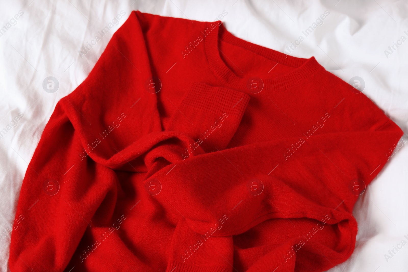 Photo of Red cashmere sweater on soft white fabric