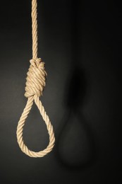 Photo of Rope noose with knot on black background, space for text