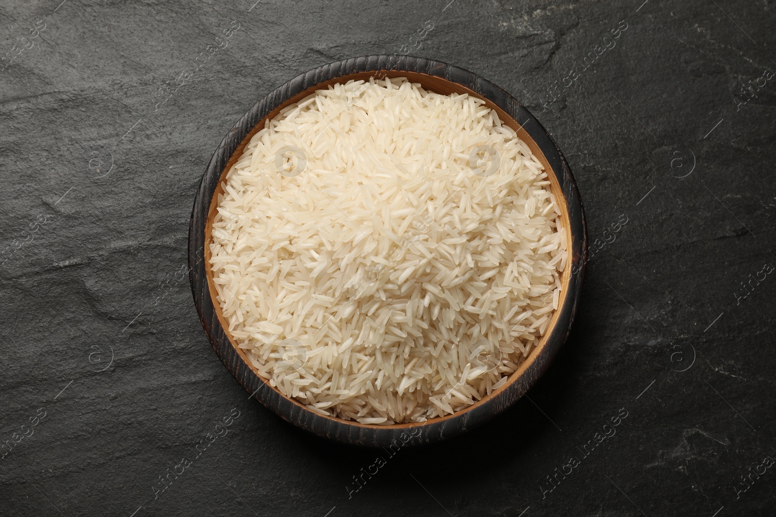 Photo of Raw basmati rice in bowl on black table, top view