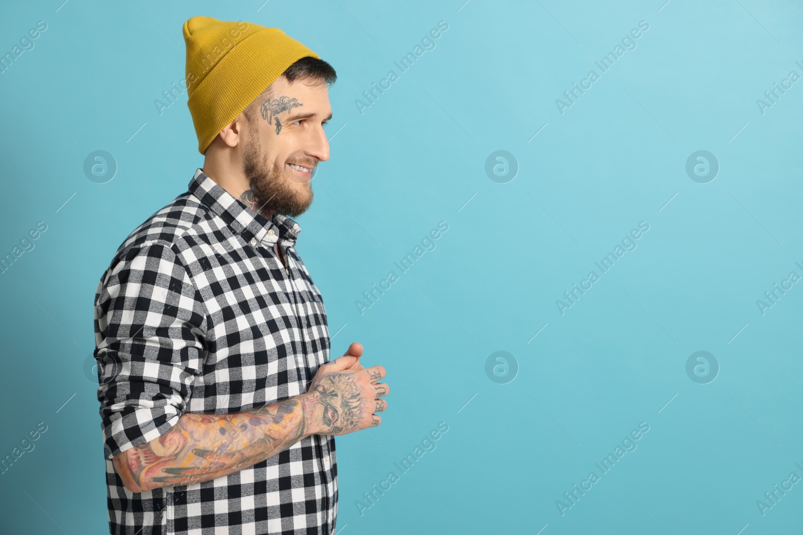 Photo of Smiling hipster man on light blue background. Space for text