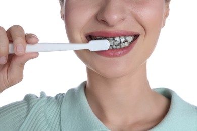 Photo of Woman brushing teeth with charcoal toothpaste on white background, closeup
