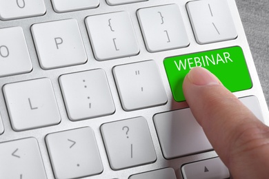 Online learning. Woman pressing button on computer keyboard with word Webinar, closeup