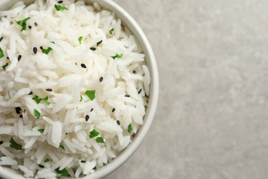 Bowl of tasty cooked rice on grey background, top view. Space for text