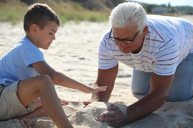 Photo of Cute little boy with grandfather spending time together on sea beach