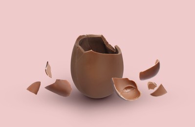 Exploded milk chocolate egg on pale pink background