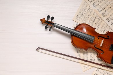 Photo of Violin, bow and music sheets on white wooden table, top view. Space for text