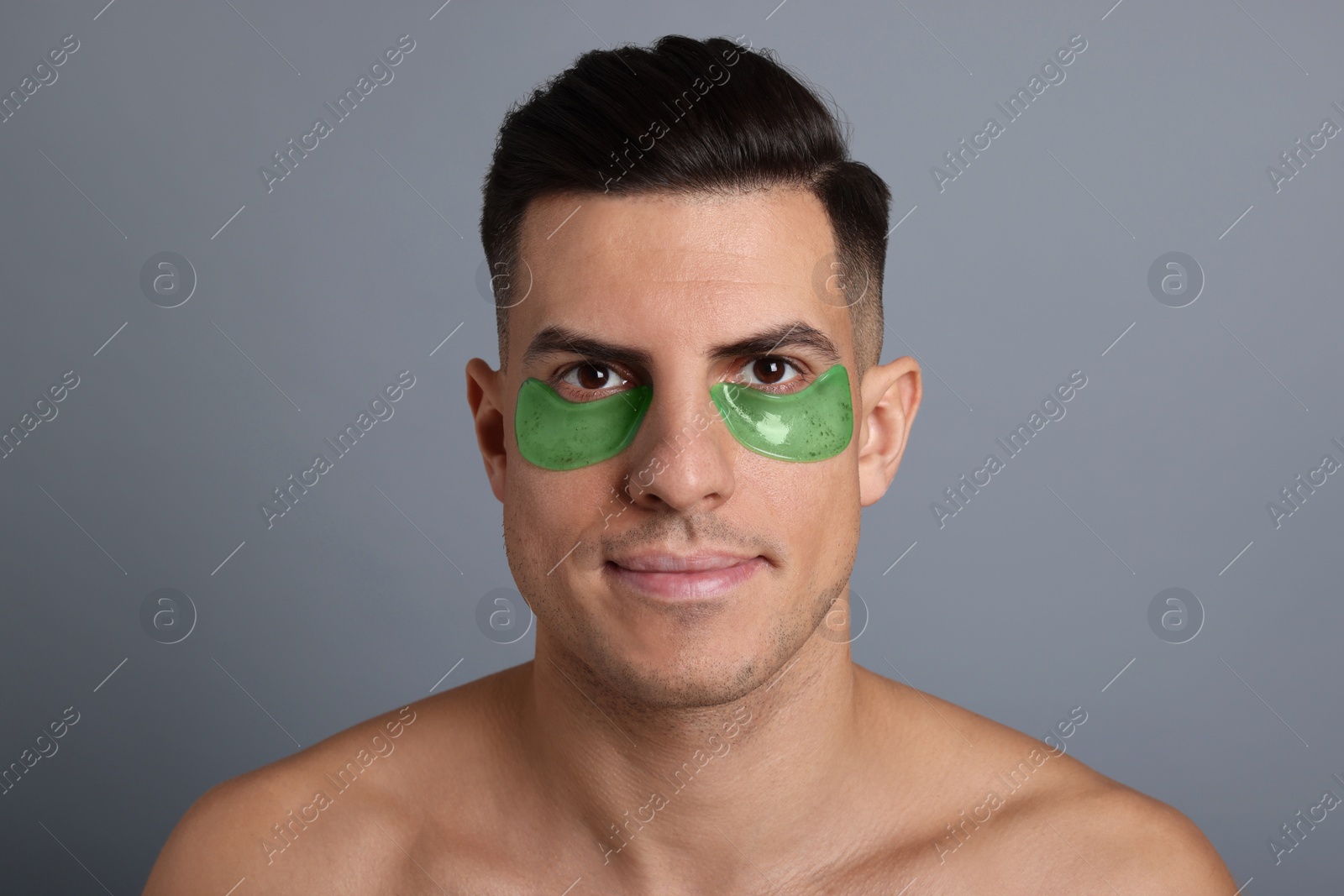 Photo of Man with green under eye patches on grey background