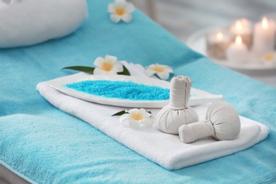 Photo of Flowers, herbal balls and sea salt on massage table in spa salon