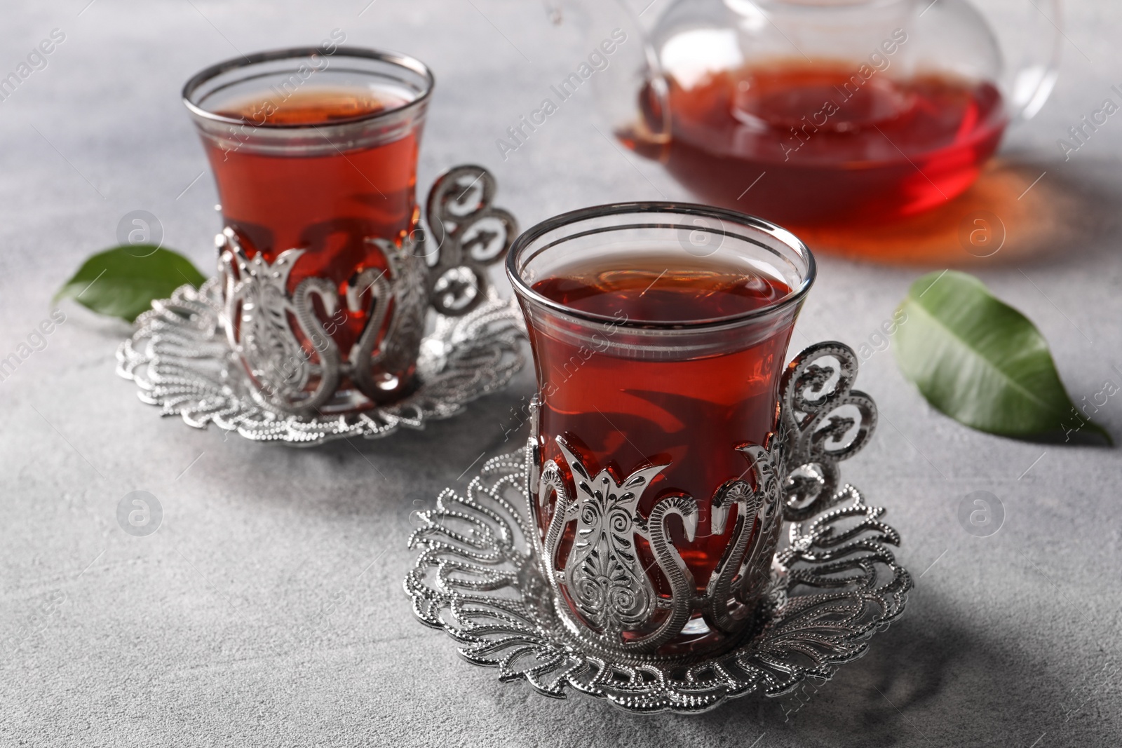 Photo of Glasses of traditional Turkish tea in vintage holders on light grey table