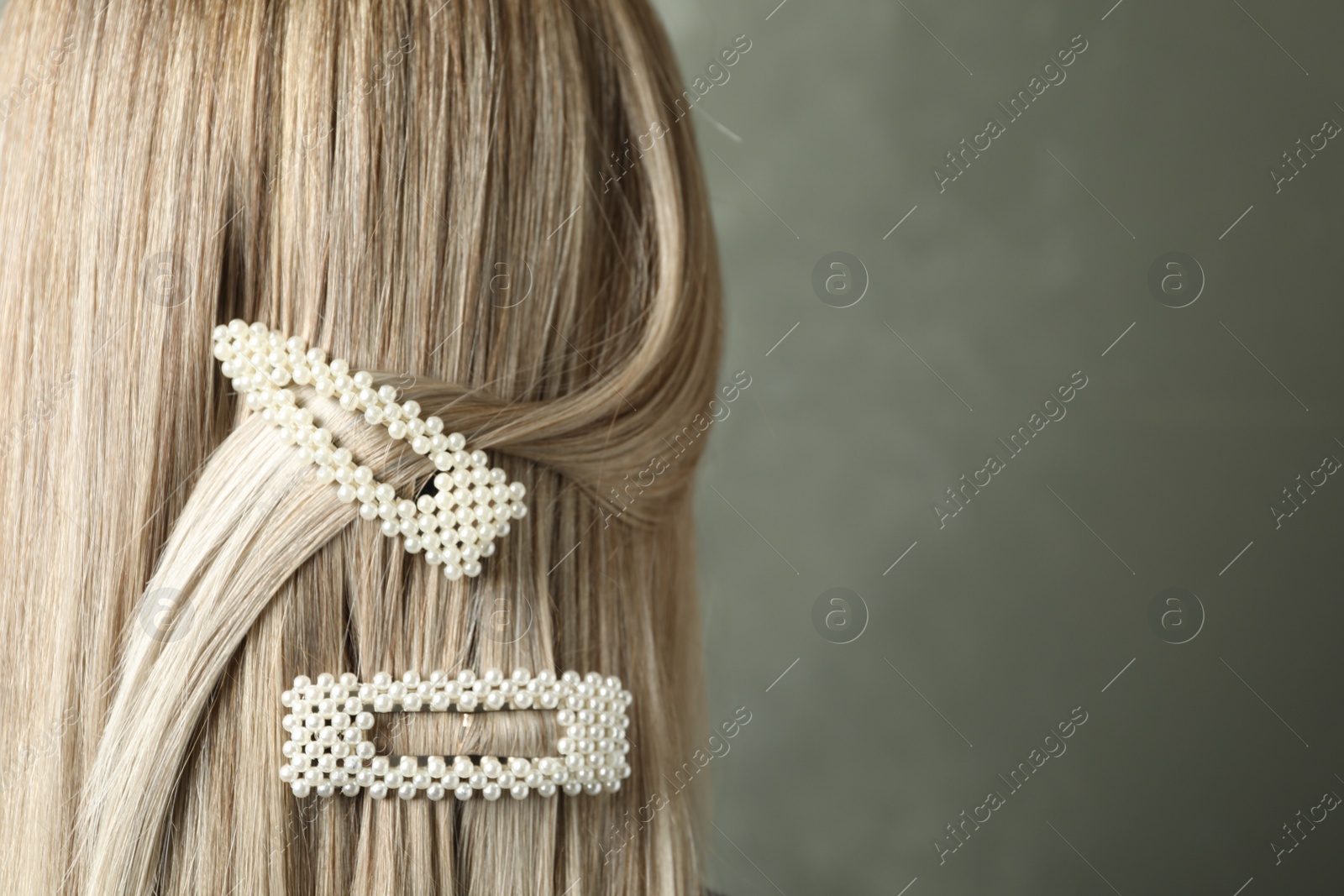 Photo of Young woman with beautiful hair clips on grey background, closeup. Space for text