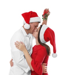 Photo of Happy couple kissing under mistletoe bunch on white background