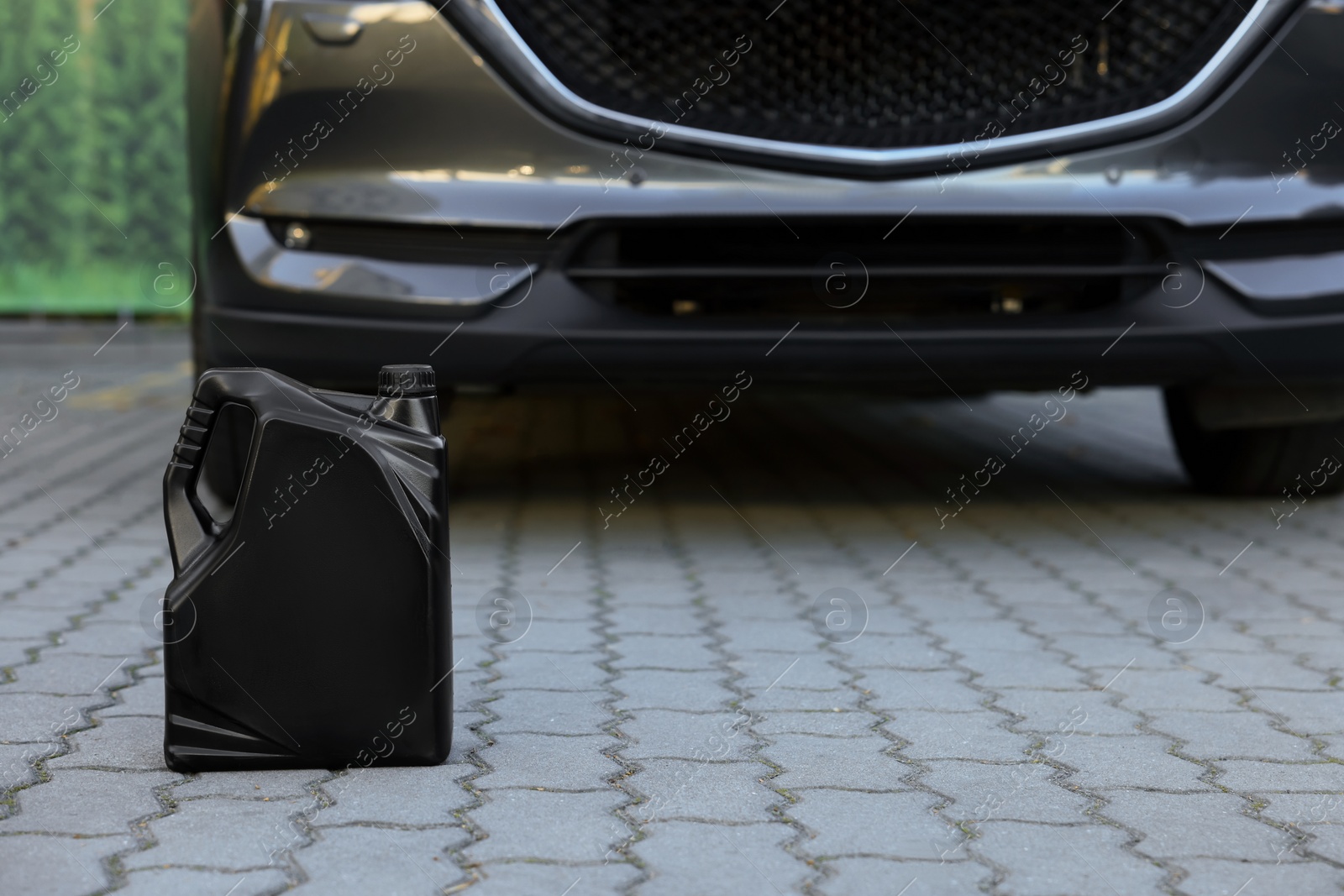 Photo of Canister with motor oil near car outdoors, space for text