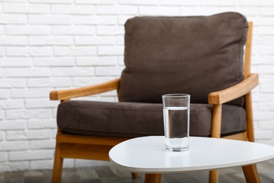 Photo of Glass of water on table in room, space for text. Refreshing drink