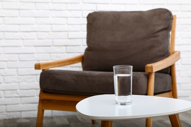 Glass of water on table in room, space for text. Refreshing drink