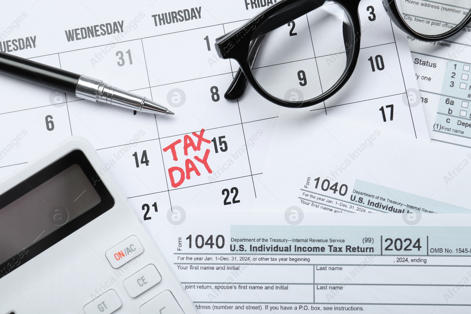 Photo of Calendar with date reminder about tax day, documents, glasses, pen and calculator, top view