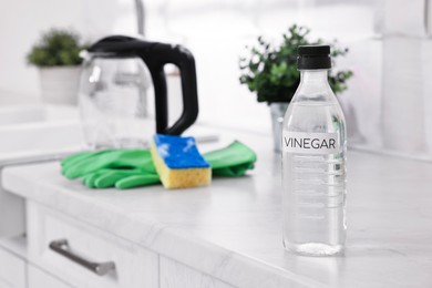 Photo of Cleaning electric kettle. Bottle of vinegar on countertop in kitchen