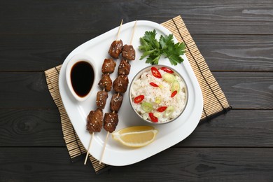Photo of Tasty chicken meat glazed in soy sauce served with rice on black wooden table, top view