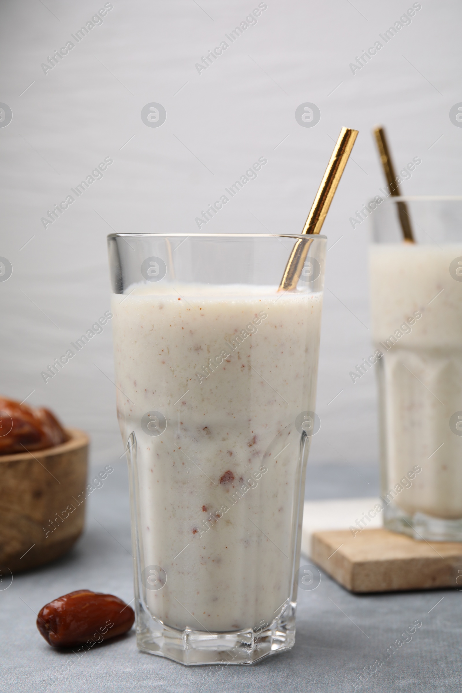 Photo of Glass of delicious date smoothie and dried fruit on light grey table