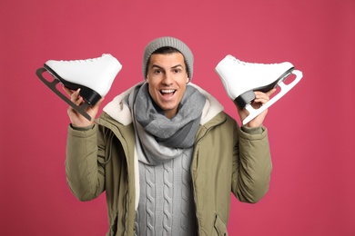 Photo of Emotional man with ice skates on pink background