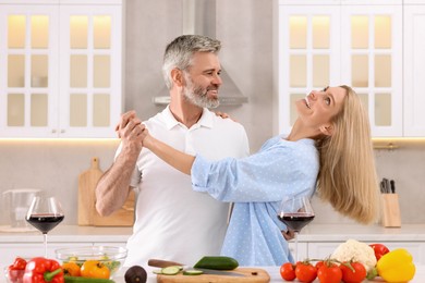 Photo of Happy affectionate couple dancing while cooking together in kitchen