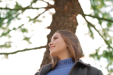 Portrait of beautiful young woman near tree on sunny day, low angle view