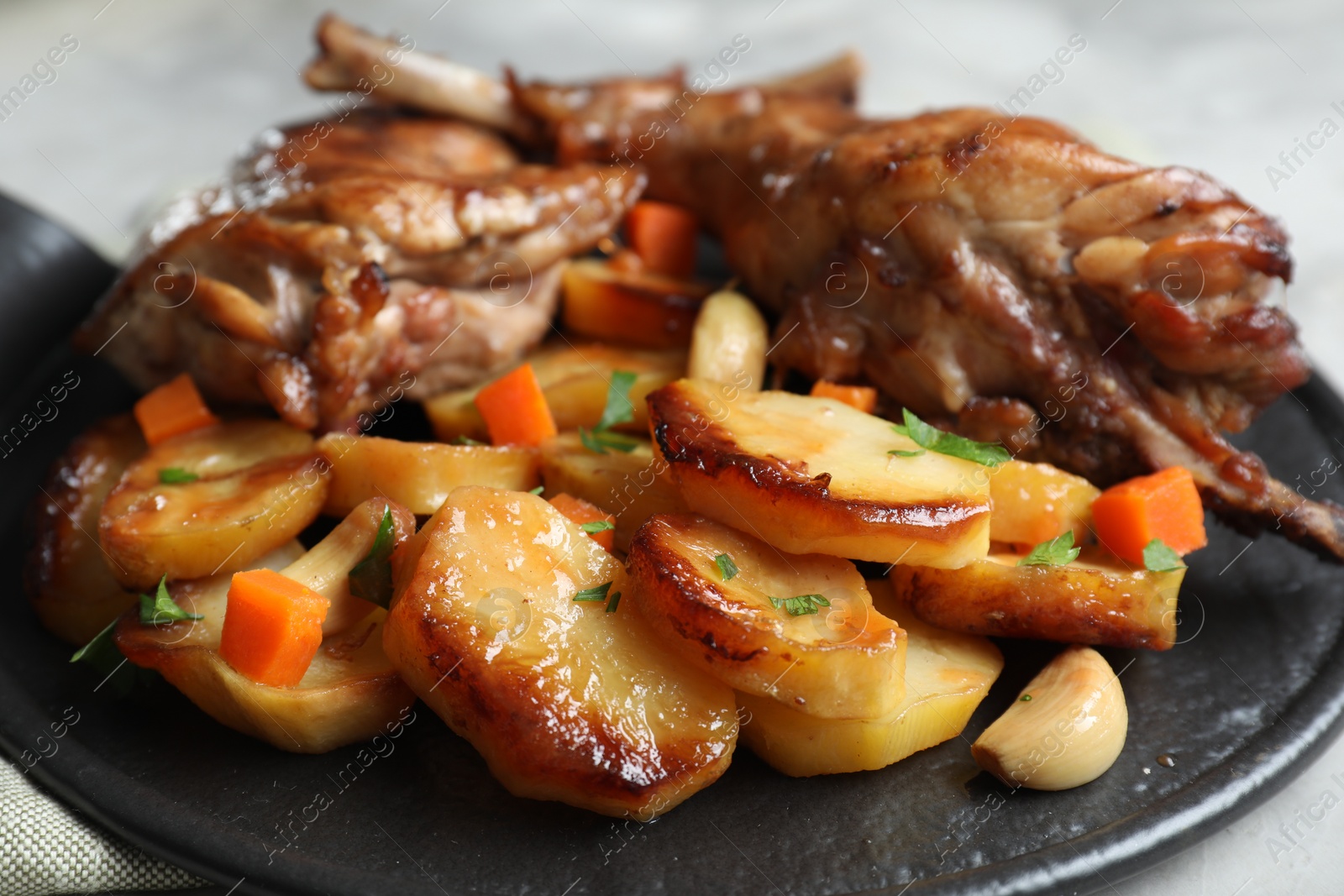 Photo of Tasty cooked rabbit meat with vegetables on table, closeup