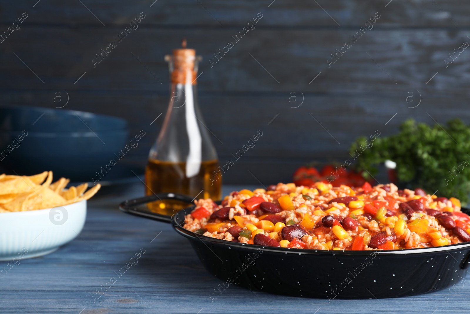 Photo of Pan with tasty chili con carne served on wooden table