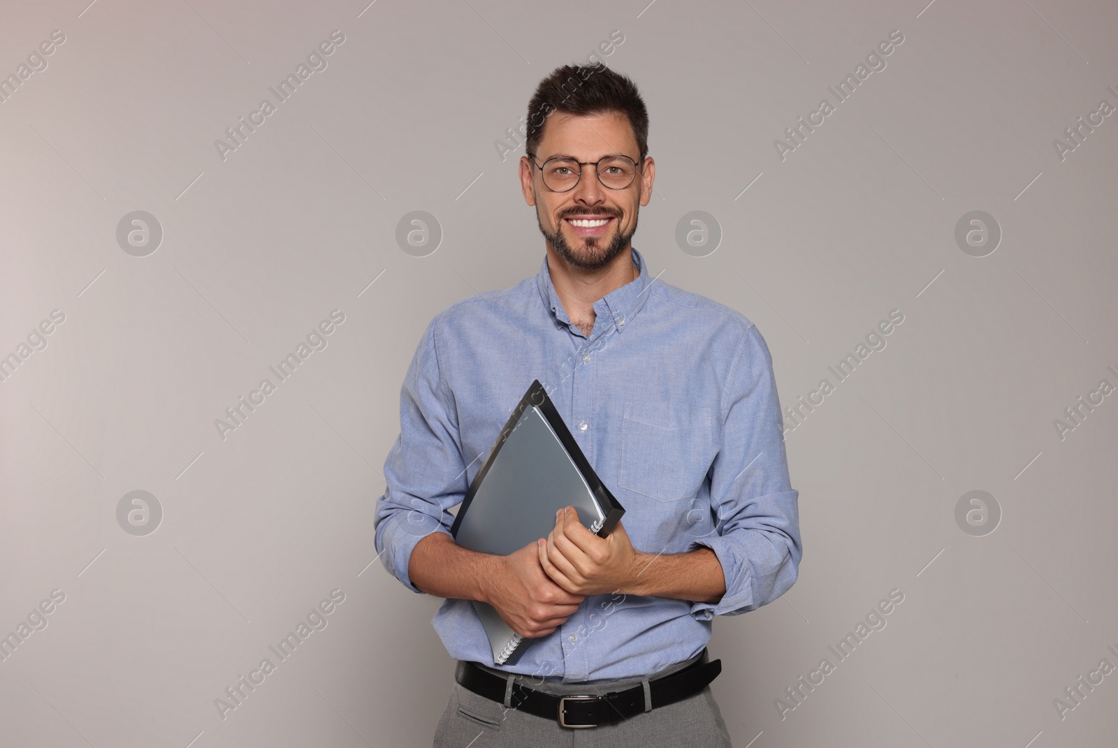 Photo of Happy teacher with glasses and stationery against beige background